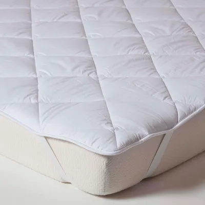 A close-up view of a white quilted mattress topper on a mattress.