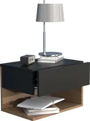 A modern black and wood tone nightstand with an open drawer and a lamp on top.