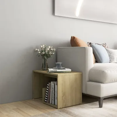A wooden side table with books and a vase of flowers next to a sofa.