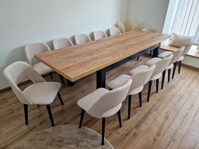 A long wooden dining table with multiple chairs arranged around it in a room.
