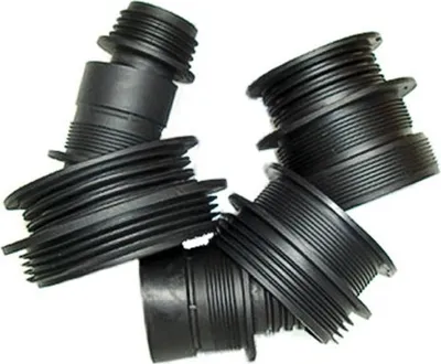 A pile of black plastic adapters with threaded ends and ribbed sections.