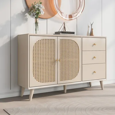 A beige sideboard with rattan doors and three drawers, set against a white paneled wall with decorative items on top.