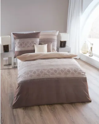 A neatly made bed with patterned bedding and pillows in a room with a large arched window.
