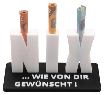 A white 3D-printed object spelling out "NIX" with rolled-up euro banknotes inserted into each letter, placed on a black base with German text.