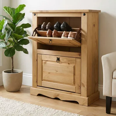 A wooden shoe cabinet with two doors and shelves, placed indoors next to a potted plant.