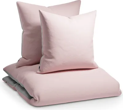 A stack of pink bedding, including two pillows and a duvet cover, is presented against a white background.