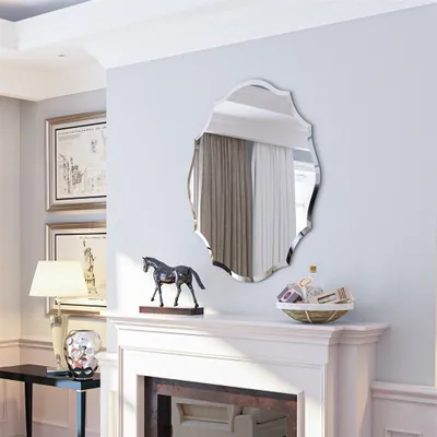 A decorative mirror is mounted above a fireplace mantel, reflecting curtains. A horse figurine and a basket of items are on the mantel. A lamp and a small table are to the left.