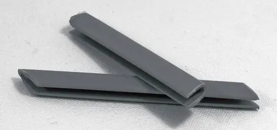 Two gray plastic profile connectors are placed on a white surface.