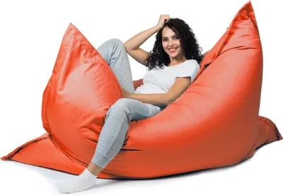 A woman is sitting on a large orange beanbag chair.