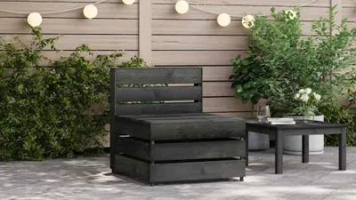 An outdoor patio scene with a dark gray wooden sofa and a matching coffee table.
