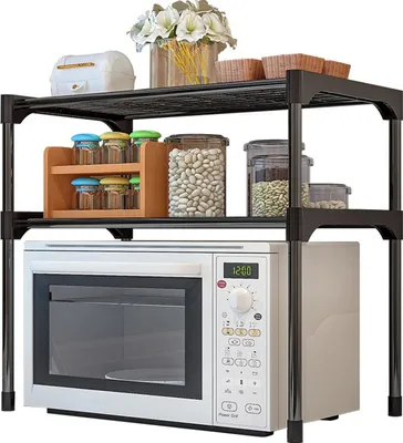 A black two-tier shelf unit with a microwave on the bottom shelf and various kitchen items on the top shelf.