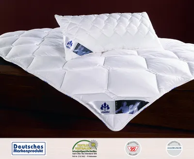 A white quilted comforter and pillow are displayed on a dark brown surface.
