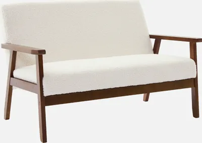 A studio shot of a cream-colored loveseat with wooden legs.