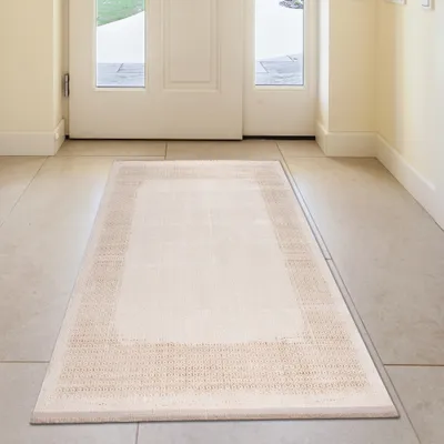 A rug placed on a tiled floor in front of a white door.