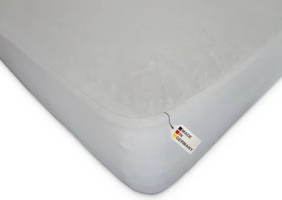 A white mattress protector with a tag indicating it is made in Germany.
