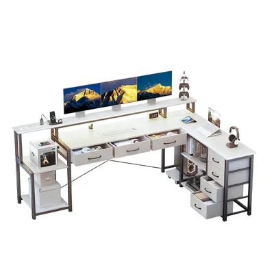 A white L-shaped computer desk with multiple monitors, drawers, and storage shelves, set against a white background.