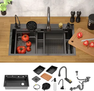 A kitchen sink with tomatoes being washed, along with various accessories and parts of a sink installation.