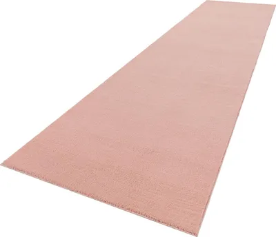 A long, narrow pink rug laid out on a white background.