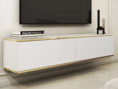 A modern white TV cabinet with gold trim is mounted on a wall.