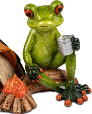 A close-up of a decorative frog figurine in a camping setting.