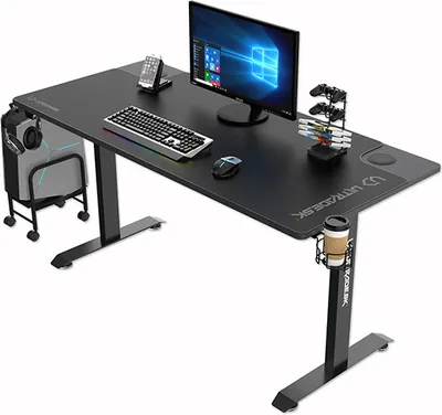 A black gaming desk with various accessories, including a computer monitor, keyboard, mouse, headphones, game controllers, a cup holder, and a phone stand.