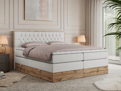 A bedroom scene featuring a king-size boxspring bed with a tufted headboard and a wooden base.