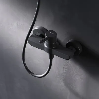 A black shower faucet mounted on a dark gray textured wall.