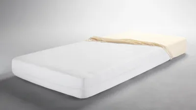 A mattress with a beige sheet partially covering it, set against a plain background.