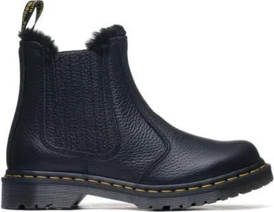 A black Dr. Martens boot with fur lining is shown against a white background.