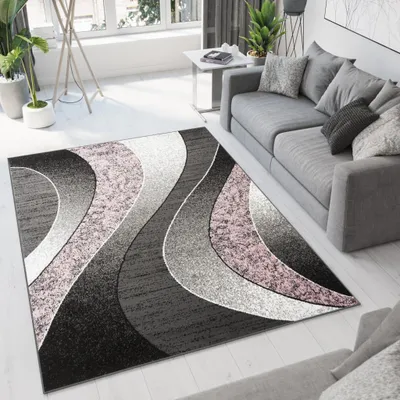 A modern living room with a gray sofa, a patterned rug, and plants.