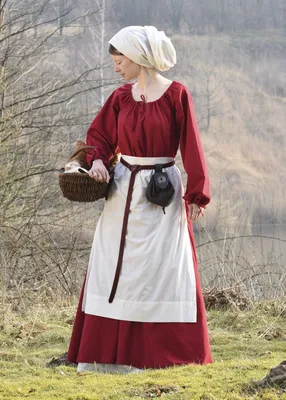 A woman in historical clothing stands in an outdoor setting.