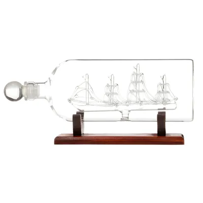 A glass bottle with a ship inside, resting on a wooden stand.