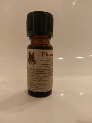Kleine braune Flasche mit einem schwarzen Verschluss. Auf dem Etikett steht "Flieder".