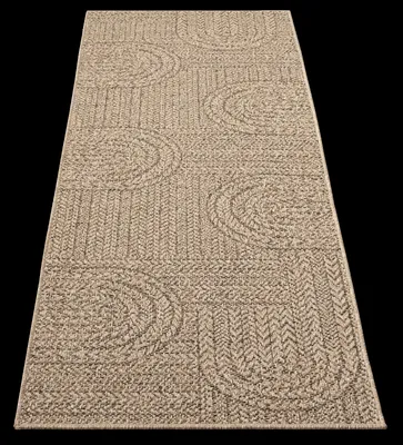 A rug with a patterned texture is shown from a diagonal angle against a black background.
