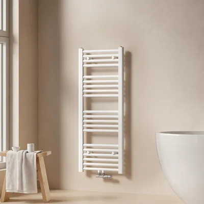A white towel radiator is mounted on a light beige wall in a bathroom, next to a window and a bathtub.