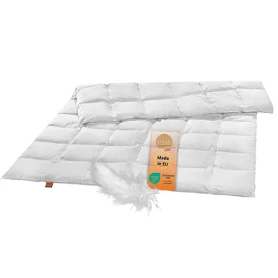 A white down comforter is laid out flat on a white background, with a small tag attached and a feather resting on the comforter.