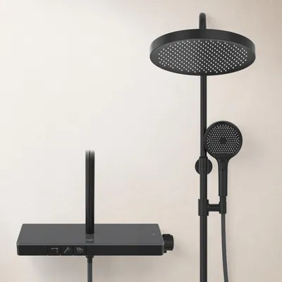 A black shower system with a large overhead shower head and a handheld shower head, mounted on a wall against a light-colored background.