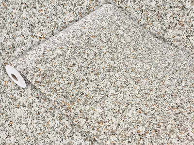 A roll of granite-patterned wallpaper is partially unrolled, showcasing the texture and color.