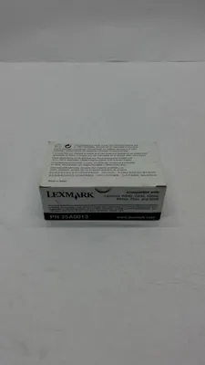 A close-up shot of a small white box with text and a logo on it, placed on a light gray surface.