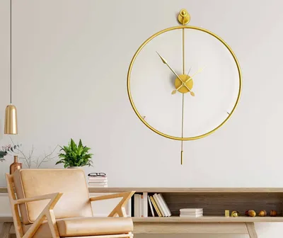 A modern living room with a gold pendulum clock on the wall, a wooden chair, and a wooden cabinet with books.