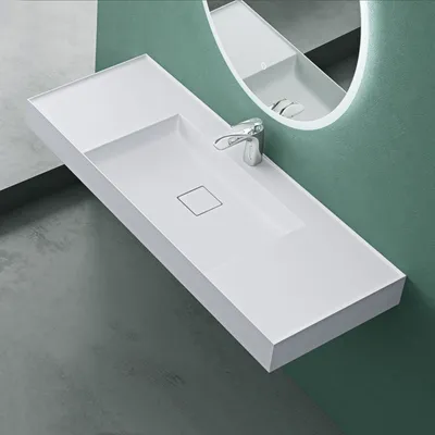 A modern white sink with a chrome faucet is mounted on a wall with a green background and a gray floor.