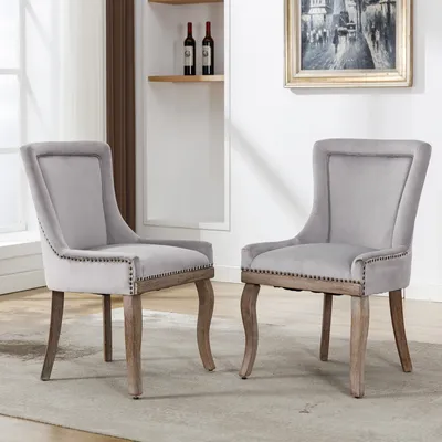 Two upholstered dining chairs with wooden legs are shown in a room setting.