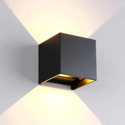 A black cube-shaped wall lamp mounted on a white wall, casting light upwards and downwards.