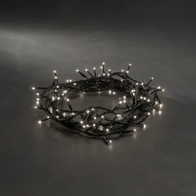 A coiled string of white LED lights with a black wire on a dark gray surface.