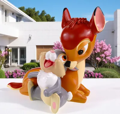 A statue of Bambi and Thumper in front of a white building with pink flowering trees.