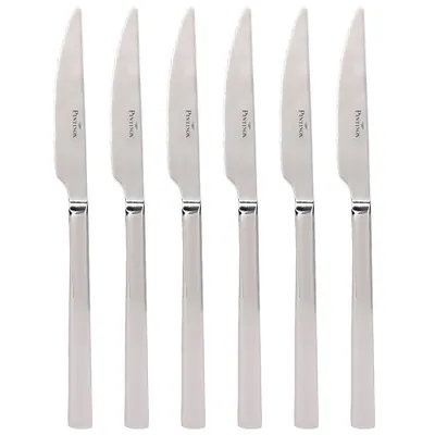 A set of six silver steak knives arranged in a row against a white background.