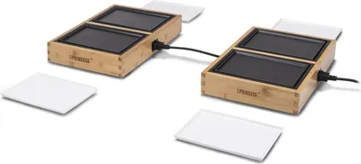 Two tabletop grills are shown connected by a wire, with white serving plates around them.