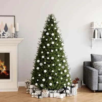 A decorated Christmas tree with presents underneath, in a living room setting with a fireplace and sofa.