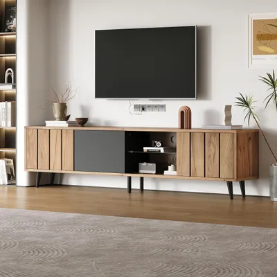 A modern living room with a TV stand and a large television mounted on the wall.