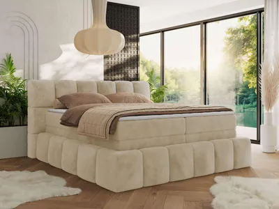 A bedroom scene with a large boxspring bed, large windows overlooking a natural landscape, and decorative elements.
